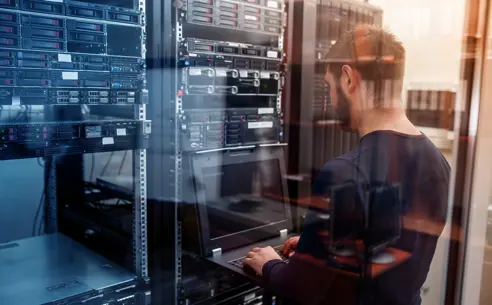 A technician working on a laptop in a server room