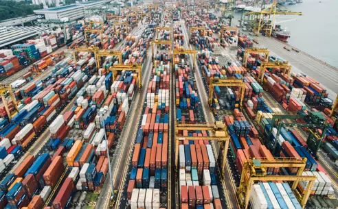 Bird's-eye view of busy container port with a great number of containers and cranes.