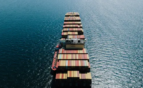 Containerskib i det blå hav fra oven