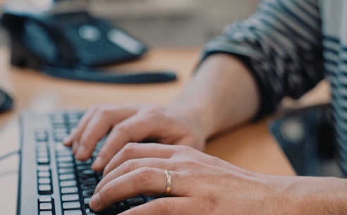 Close-up of hands typing on a keyboard in an office setting