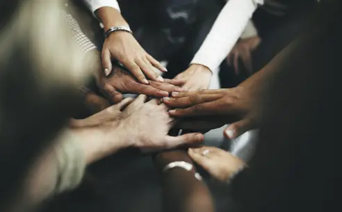 En gruppe af forskellige hænder placeret sammen i en cirkel, som symboliserer teamwork