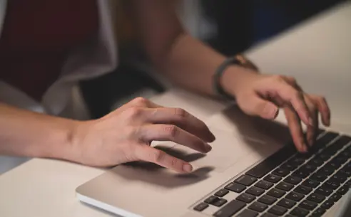 Close-up of a person typing on a laptop
