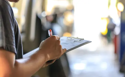 Close-up of a person writing on a clipboard